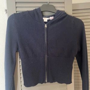 Mörkblå kofta med dragkedja - Snygg mörkblå kofta från Gina Tricot i stickat material. Croppad modell med ribbad nederdel och långa ärmar. Utrustad med huva och hel dragkedja framtill. Super skönt material!