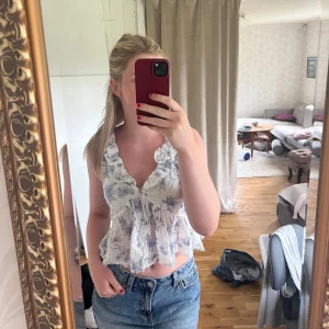 Vit blommig volangblus - Supersöt vit blus med blått blommönster. Säljer då den inte kommer till användning, använd ca 3 ggr så i fint skick. Hör av dig vid frågor, pris går att diskutera🫶