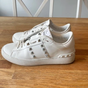 Valentino Garavani Rockstud sneakers - Snygga vita Valentino sneakers med silverfärgade nitar och snörning. Köpte dem av en tjej på vinted men dem satt tyvärr för litet på mig. Personen hade även tappat bort lådan så den medföljer tyvärr inte. Skorna är i jättebra skick bara lite smuts som är enekelt att ta bort