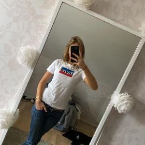 Vit Levi's t-shirt med logga - Vit t-shirt från Levi's med klassisk logga i blått och rött framtill. Modellen är kortärmad och har en normal passform. Perfekt till jeans för en clean och enkel stil.🌟💘stl 12A/152cm