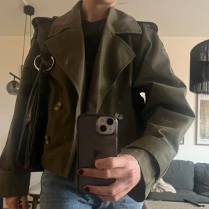Kort trench olivgrön  - Säljer denna korta trenchcoat från HM i Storlek S !  Använt en del men inga tydliga tecken på slitage eller andra defekter återfinns. Bilderna är lite otydliga så bara PMa mig så kan jag skicka fler✨