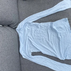 Ljusblå långärmad intimisimi - En enkel och stilren ljusblå klänning med lång ärm. Klänningen har en rak passform och är tillverkad i ett tunt, mjukt material som känns skönt mot huden. Perfekt för dig som gillar minimalistisk stil och vill ha något bekvämt och snyggt.