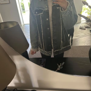 Oversized jeansjacka i tvåtonad denim från HM - Säljer en oversized jeansjacka i två olika denimfärger, med coola råa kanter och kontrastsömmar. Jackan har stora bröstfickor med knapp, klassisk krage och knäppning framtill. Perfekt för dig som gillar streetstyle och vill sticka ut.