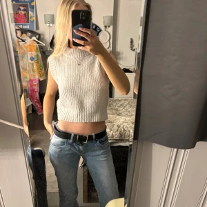 Grå ribbad stickad topp från Collusion - Säljer en går, ribbad och croppad stickad topp från Collusion. Toppen är ärmlös med hög hals i storlek 32