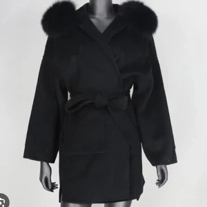 Svart kappa med fuskpäls och bälte - Stilren svart kappa med stora fluffiga fuskpälsdetaljer på axlarna och knytbälte i midjan. Jackan har omlottstängning, raka ärmar och två stora fickor framtill. Perfekt för dig som vill ha en trendig och mysig look under kyliga dagar. Använd fåtal gånger och passar storlek Xs till L skulle jag säga.