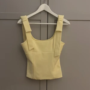 Gul linnetopp från Zara - Supersöt ljusgul linnetopp från Zara i storlek XS. Nyskick och aldrig använd, prislappen finns kvar! De dekorativa banden är olika långa men det är inget man tänker på💓💓 Nypris 329kr