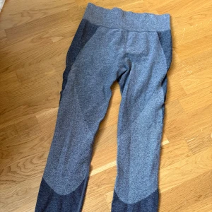 Grå träningstights från Cubus - Mörkgrå och ljusgrå träningstights från Cubus i storlek L. De har bred midja och snygga kontrastpaneler på benen. Perfekta för gymmet eller löprundan, med stretchigt och mjukt material som sitter skönt hela dagen.