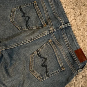 Low waist bootcut jeans från Pepe jens  - Snygga blå bootcut jeans från Pepe jeans med klassisk femficksdesign och vågig brodyr på bakfickorna. Jeansen har en såå fin låg midja❤️Har lite slitningar längst ner på baksidan men är inget man tänker på❤️❤️