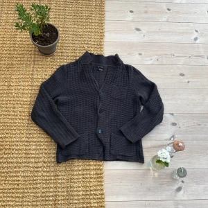 Grå kofta från Massimo Dutti i bomull - Säljer en grå kofta från Massimo Dutti i 100% bomull. Koftan har en snygg stickad struktur, tre knappar framtill, v-ringning och fickor. Perfekt för lager-på-lager och chill stil.