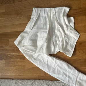 Vit linneskjorta från Zara S - Säljer en stilren vit skjorta från Zara i storlek S. Skjortan är tillverkad i linne, har långa ärmar och snygga guldknappar vid manschetterna. Perfekt för dig som gillar en clean och fräsch look.