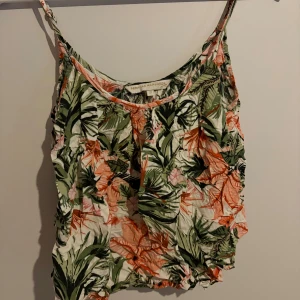 Blommig linnetopp från Pernilla Wahlgren - Supersöt linnetopp från Pernilla Wahlgren med blommigt mönster i grönt, rosa och vitt. Tunt och luftigt material, perfekta smala axelband och avslappnad passform. Perfekt för varma dagar och sommarhäng!