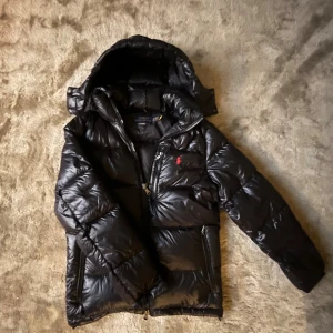 Svart pufferjacket från Polo Ralph Lauren.  - Säljer en stilren svart pufferjacket från Ralph Lauren, perfekt för dig som vill känna dig varm och mysig hela tiden. Rekommenderar att använda den från oktober till när de första snön kommit. Oktober - februari. Är i storlek Xs men sitter mer som S 