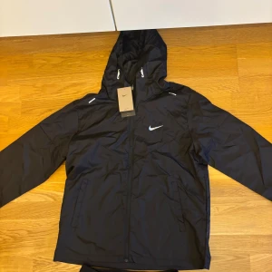 Svart vindjacka från Nike  - Helt ny. Tunn svart vindjacka perfekt för hösten. Storlek L passar även M