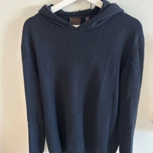 Mörkblå Kashmir Hoodie från Oscar Jacobson - Mysig mörkblå hoodie från Oscar Jacobson i storlek L men passar även M. Tillverkad i Italien i mjuk ull, med klassisk huva och långa ärmar. Perfekt för dig som gillar stilrena och bekväma plagg med premiumkänsla.