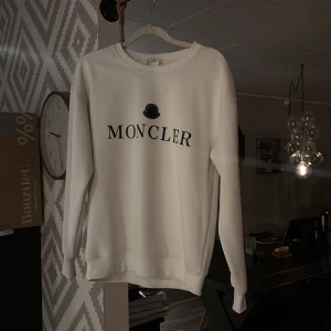 Vit Moncler tröja - Säljer denna feta Moncler tröja eftersom att jag har växt ut den. Den har två små blåa fläckar men inget som syns när man har på sig den. Storleken är S men passar också xs skulle jag säga. Hör av dig vid frågor!