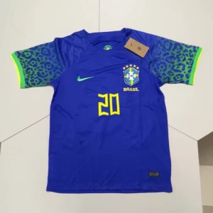 Blå Brasil Vini Jr. fotbollströja Nike - Snygg blå Brasilien fotbollströja från Nike med Vini Jr. och nummer 20 i gult på ryggen. Kortärmad modell med leopardmönstrade ärmar i blått och grönt, samt gula och gröna detaljer. Tillverkad i lätt, tekniskt material med CBF-emblem på bröstet.