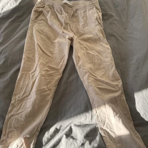 Beige linnebyxor från Selected Homme - Snygga beige linnebyxor från Selected Homme med avslappnad passform och elastisk midja med snörning. Perfekta för chill dagar och har praktiska sidofickor. Materialet är linne som ger en skön och luftig känsla. Lite mindre i sin storlek men ändå en M.