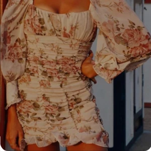 Blommig kortklänning från Zara - Supersöt kortklänning från Zara med ljusbeige botten och blommigt mönster i rosa och grönt. Klänningen har puffiga långärmar, fyrkantig urringning och rynkade detaljer längs hela kroppen. Den är liten i storlek, fråga inte om bild på för jag får inte på mig klänningen:)