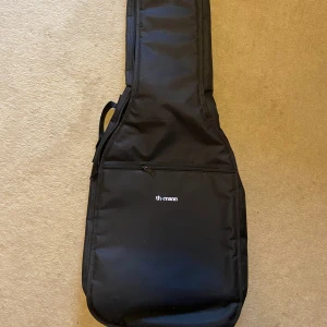 Gitarrfodral väska - Säljer ett svart gitarrfodral med ett stort ytterfack med dragkedja. Väskan är tillverkad i slitstark polyester. Har aldrig använt den, så den är som ny