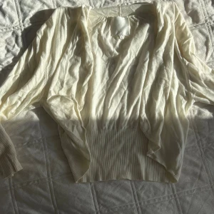 Ljusbeige kofta från AWear - Säljer en ljusbeige kofta från AWear i storlek L. Koftan har bred ribbad mudd nedtill och vid ärmslut, samt en luftig och avslappnad passform. Perfekt att slänga över en topp för en chill look.