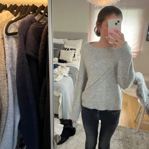 Ljusgrå stickad kofta med knappar - Supermysig ljusgrå stickad kofta med snygg omlott-design och dekorativa knappar framtill. 