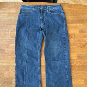 Blå jeans från Loro Piana, storlek 33 - Snygga blå jeans från Loro Piana i klassisk straight fit. Jeansen har fem fickor, orangea sömmar och är tillverkade i 97% bomull. Perfekt för dig som gillar stilrena och tidlösa jeans med exklusiv känsla.