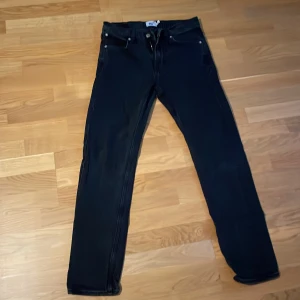 Svarta jeans från 157, W29 L32 - Svarta jeans från 157 med klassisk femficksdesign och raka ben. Jeansen har normal passform och är tillverkade i ett mjukt denimtyg som sitter skönt hela dagen. Perfekta för dig som gillar en enkel och stilren look.