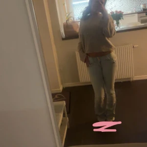 Ljusblå bootcut jeans - Säljer ett par ljusblå jeans med bootcut passform och klassisk femficksdesign. Jeansen har låg midja och är tillverkade i mjukt denimtyg som sitter snyggt och bekvämt. Perfekta för dig som gillar en retro vibe och vill ha ett par jeans som sticker ut. Har däremot flera små hål och ett av banden är borta.