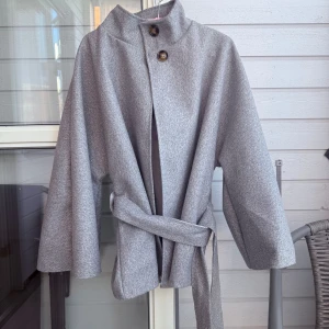 Grå Poncho jacka/kappa - Fick precis hem den men tycker ej den passade på min kroppstyp. Krånglig retur så väljer att sälja den vidare istället. Köpt på linasljuvating.se. One size passar ungefär stl. 36-46.