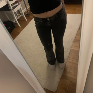 Svarta/mörk gråa bootcut jeans från Gina  - Säljer ett par svarta/mörk gråa bootcut jeans från Gina tricot i storlek 38. Jeansen har klassisk femficksdesign, låg midja och är tillverkade i ett mjukt denimtyg. Snygg passform med utsvängda ben💕