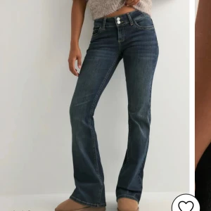 Mörkblå bootcut jeans med broderi - Snygga mörkblå jeans med bootcut passform och coolt gult broderi på bakfickorna. Jeansen har dubbla knappar i midjan och klassiska fickor fram och bak. Perfekta för dig som gillar en tidlös men trendig look. Helt nya med lappen kvar då de va för små. 