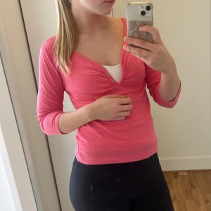 Rosa långärmad topp från H&M - Säljer en rosa långärmad topp från H&M i storlek S. Toppen har v-ringning med knappar framtill och lätt rynk vid bysten. Tillverkad i mjuk bomull och har en smickrande passform som sitter snyggt på kroppen.