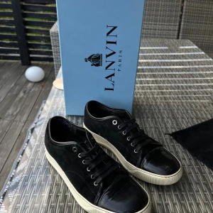 Svarta sneakers från Lanvin Paris - Svarta sneakers från Lanvin Paris i bra skick med snygg kontrast mellan mocka och lackad skinn på tån. Kommer med originalkartong såklart. Nypris: ca 4000-4500kr. Priset kan diskuteras och hör av er vid funderingar!