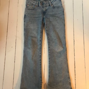 Lågmidjade ljusblå bootcut jeans - Ljusblå jeans från 157 med låg midja och bootcut-ben. Snygga broderade detaljer på bakfickorna och dubbla knappar framtill. Klassisk femficksmodell i mjukt denimtyg, perfekt för dig som gillar en avslappnad och trendig look.