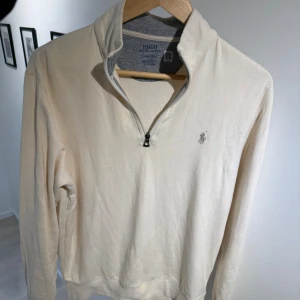 Polo Ralph Lauren tröja  - Säljer en stilren vit/beige långärmad tröja från Polo Ralph Lauren med grått innerfoder i kragen. Den är halfzip, storlek S och kostar nypris 2349kr. Den är i bra skick och bara att skriva vid frågor och funderingar.😁