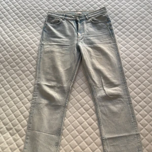Ljusblå jeans från gina tricot - Säljer ett par ljusblå jeans från gina tricot, modell perfect jeans. Klassisk femficksdesign, raka ben och normal passform. Jeansen har en snygg tvättad look och är tillverkade i bomull. Perfekt för dig som gillar enkel och stilren denim. Har slitning på fållen vid fötterna men de ska vara så!