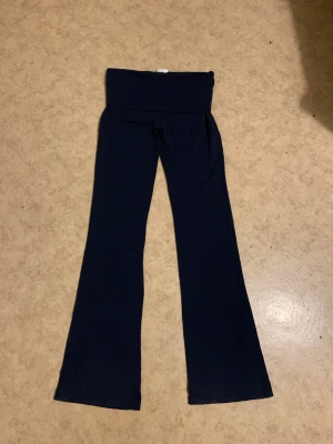 Mörkblå bootcut byxor från Gina Tricot - Snygga mörkblå Yoga pants från Gina Tricot i mjukt bomullsmaterial. De har låg/hög midja med bred linning och ett stilrent, enkelt utseende. Perfekta för dig som gillar bekväma och trendiga byxor med lite utsvängda ben.