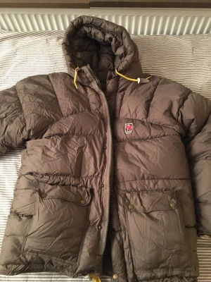 Olivgrön dunjacka från Fjällräven - Säljer en olivgrön dunjacka från Fjällräven med huva.  Använd 1 vinter. Bra skick. Kan gå ner i pris vid snabb affär i Stockholm :)
