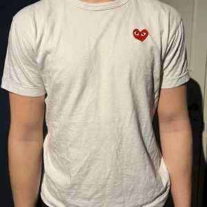 Vit Comme des Garçons Play t-shirt - Säljer en vit t-shirt från Comme des Garçons Play i storlek L, men passar som en M om lösare passform önskas. Tröjan är av herrmodell men skulle säga att den är unisex. Varan har tecken på användning men det är ingenting märkvärdigt 🙌.