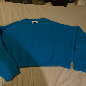 Blå croppad tröja från Zara - Säljer en blå croppad tröja från Zara i storlek S. Tröjan har lång ärm, rund hals och är tillverkad i mjuk polyesterblandning. Enkel och stilren design som passar perfekt till jeans eller kjol. Färgen är klarblå och materialet känns fluffigt och bekvämt.