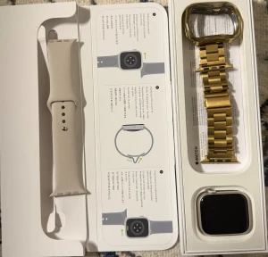 Apple Watch Series 9 - Apple Watch Series 9 i originalförpackning, komplett med vit silikonrem och extra guldlänkarmband. Smartklockan har en stor, tydlig skärm och modern design. Produkten ser ut att vara i nyskick utan synligt slitage eller defekter. Perfekt för träning, hälsa och vardagsbruk.