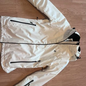 Vit skidjacka Cross Sportswear - Snygg vit skidjacka från Cross Sportswear med svarta dragkedjor och praktiska fickor.