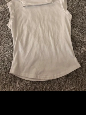 Vit polotopp från SHEIN - Säljer en enkel och stilren vit polotopp från SHEIN i storlek S. Toppen är ärmlös med hög krage och har en rak passform. Tillverkad i mjuk och lätt polyester, perfekt att matcha med jeans eller kjol för en clean look.