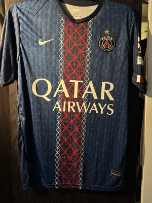 Fotbollströja psg  - Bilderna visar en fotbollströja från PSG med Qatar Airways som sponsor, Nike Dri-Fit material och spelarnamn D. Doué med nummer 14. Priset kan diskuteras