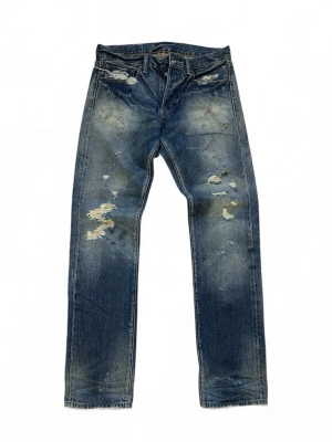 Slim jeans från Ralph Lauren Denim & Supply - Slim fit jeans från Ralph Lauren Denim & Supply i klassisk blå tvätt med slitna och trasiga detaljer. Byxorna har raka ben, fem fickor och patch med amerikanska flaggan bak. Materialet är robust denim i bomull. (Sample) Väldigt rare, 32/32 Helt nya!