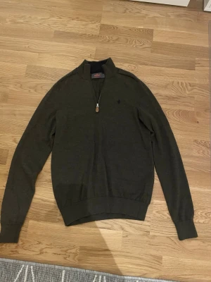Brun half zip tröja Morris S - Snygg brun långärmad tröja från Morris i storlek S, tillverkad i 100% merinoull. Tröjan har en stilren half zip-dragkedja framtill och en liten broderad logga på bröstet. Perfekt för dig som gillar klassisk och enkel stil.