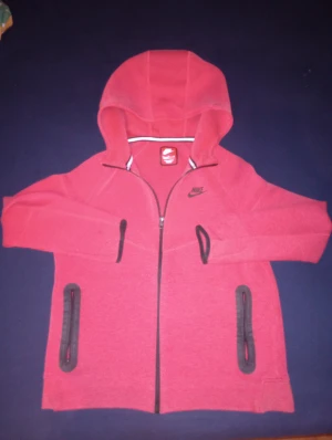 Röd nike tech fleece  - Röd nike tech Fleece från nike röd färg. Använd 3 gånger och  kommer  i storlek 158-170 XL och ifall ni vill ha byxor med kostar det extra 300 kr kontakta mig ifall ni vill ha byxor också.