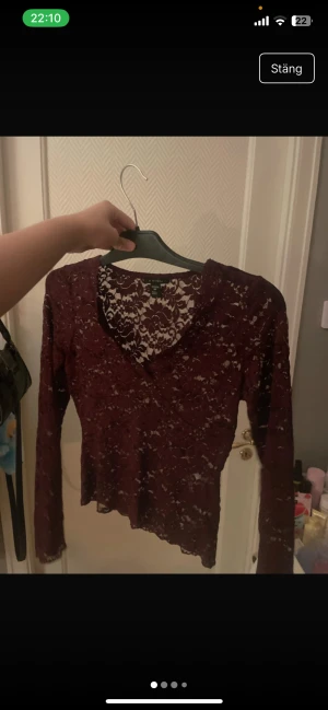 Vinröd spetsblus från newyorker  - Säljer en vinröd långärmad blus från Amisu med v-ringad hals och genomgående spetsmaterial. Blusen har ett blommigt spetsmönster och är figurnära i modellen. Perfekt för dig som gillar detaljer och vill sticka ut med en snygg topp.