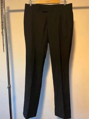 Svarta kostymbyxor  - Snygga svarta kostymbyxor från Vero Moda med klassisk rak passform. Byxorna har bälteshällor, pressveck och två bakfickor med knapp. Tunnare material. Strl. 32/32