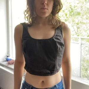 Brun jeanskorsett från Holzweiler - Säljer en brun korsettopp från Holzweiler i jeansmaterial med markerade sömmar och breda axelband. Toppen har dragkedja bak och en croppad passform som ger en edgy vibe. Perfekt att styla med höga byxor eller kjol för en cool look.